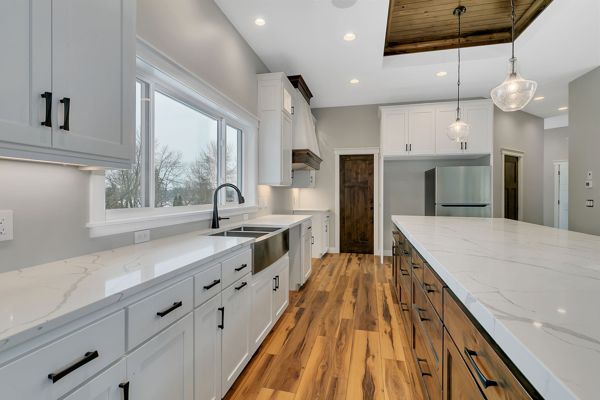 A kitchen with white cabinets and hardwood floors and a large island.