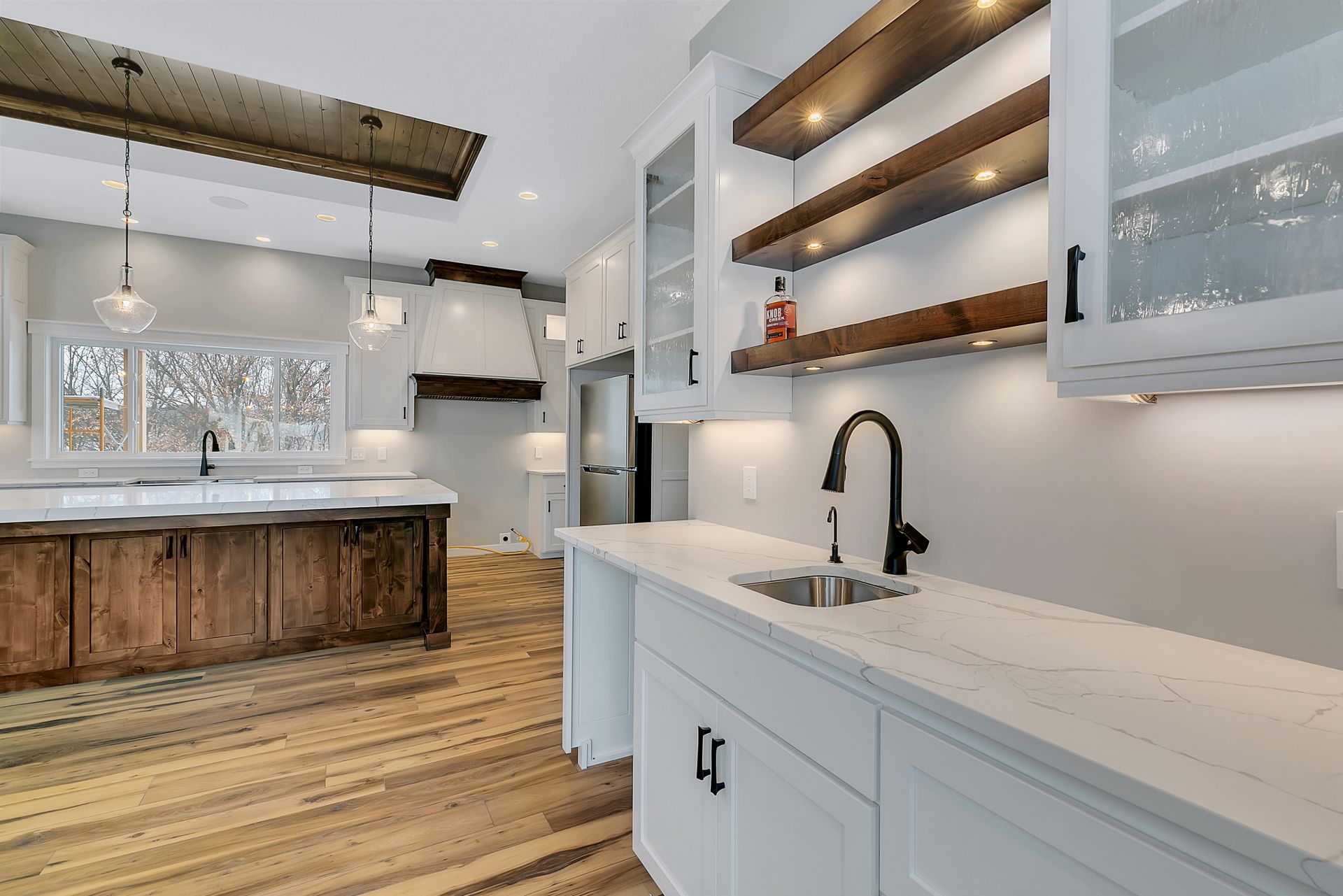 A kitchen with white cabinets and wooden floors and a sink.