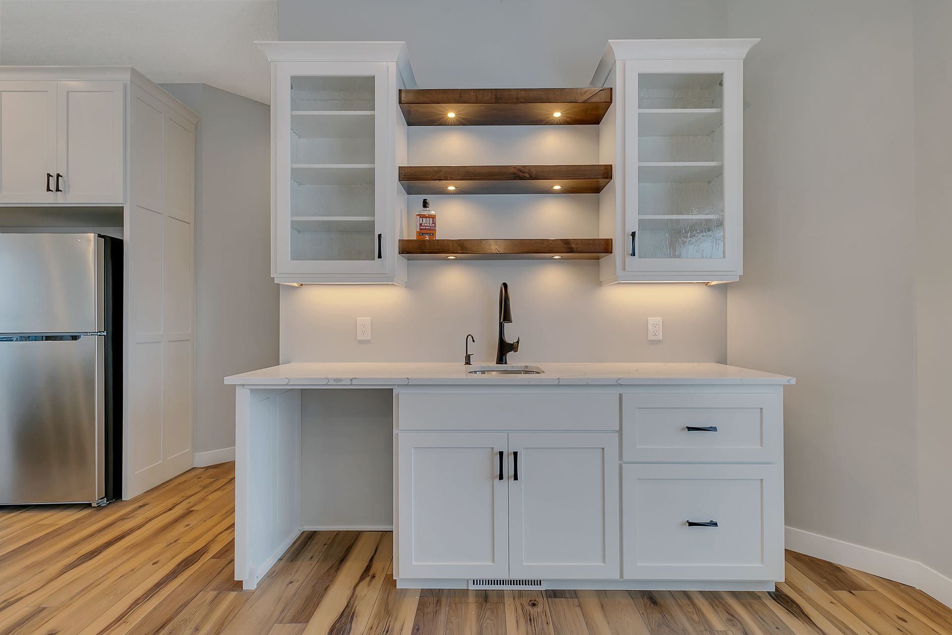 A kitchen with white cabinets , a sink , and a refrigerator.
