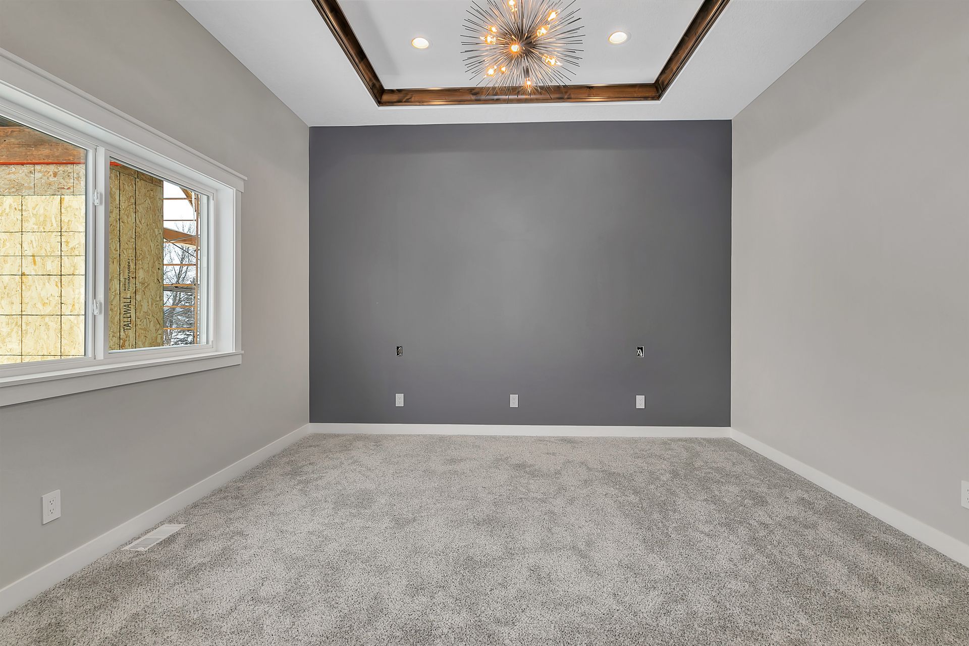 An empty room with a gray wall and a chandelier.