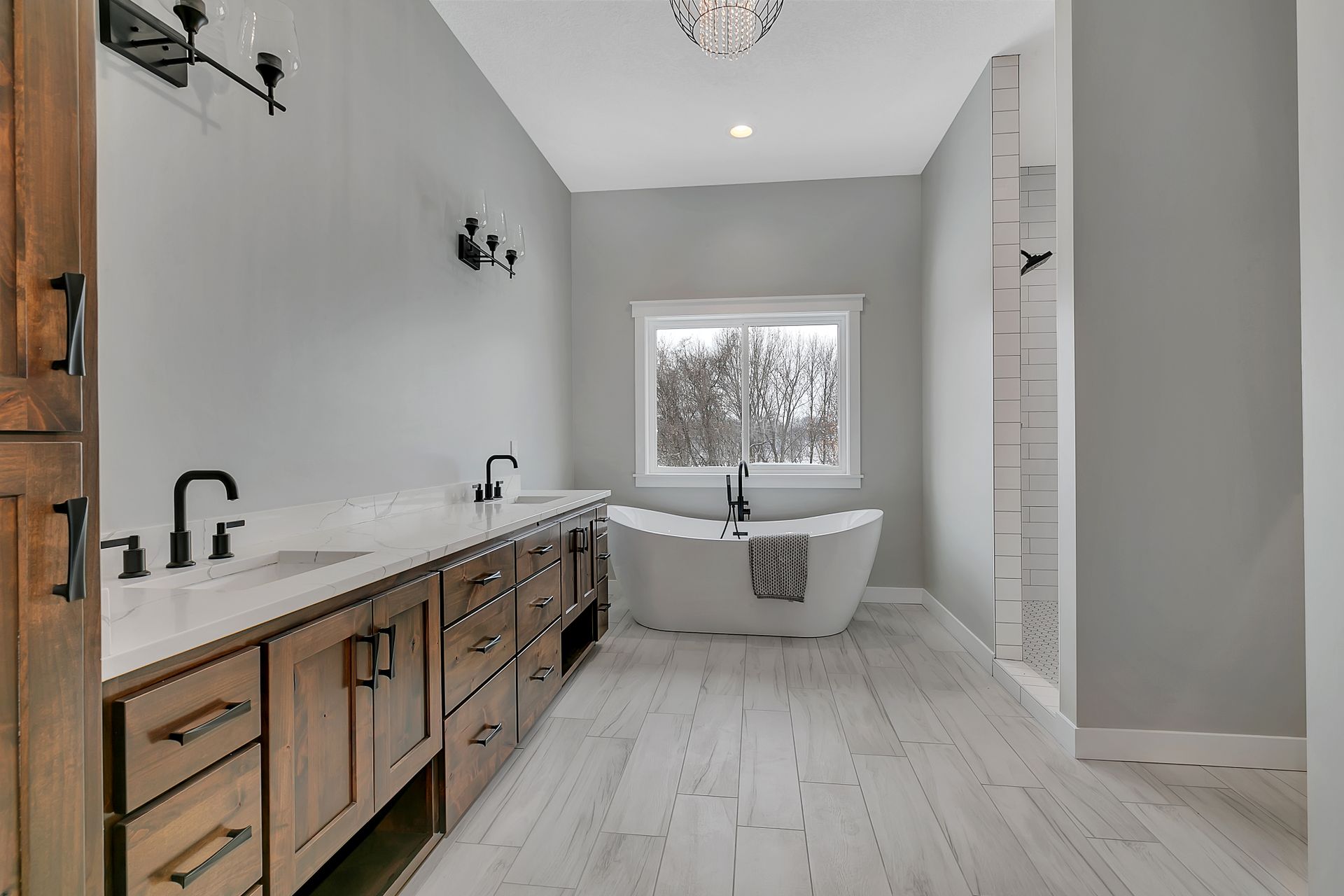 A bathroom with two sinks , a tub , and a window.