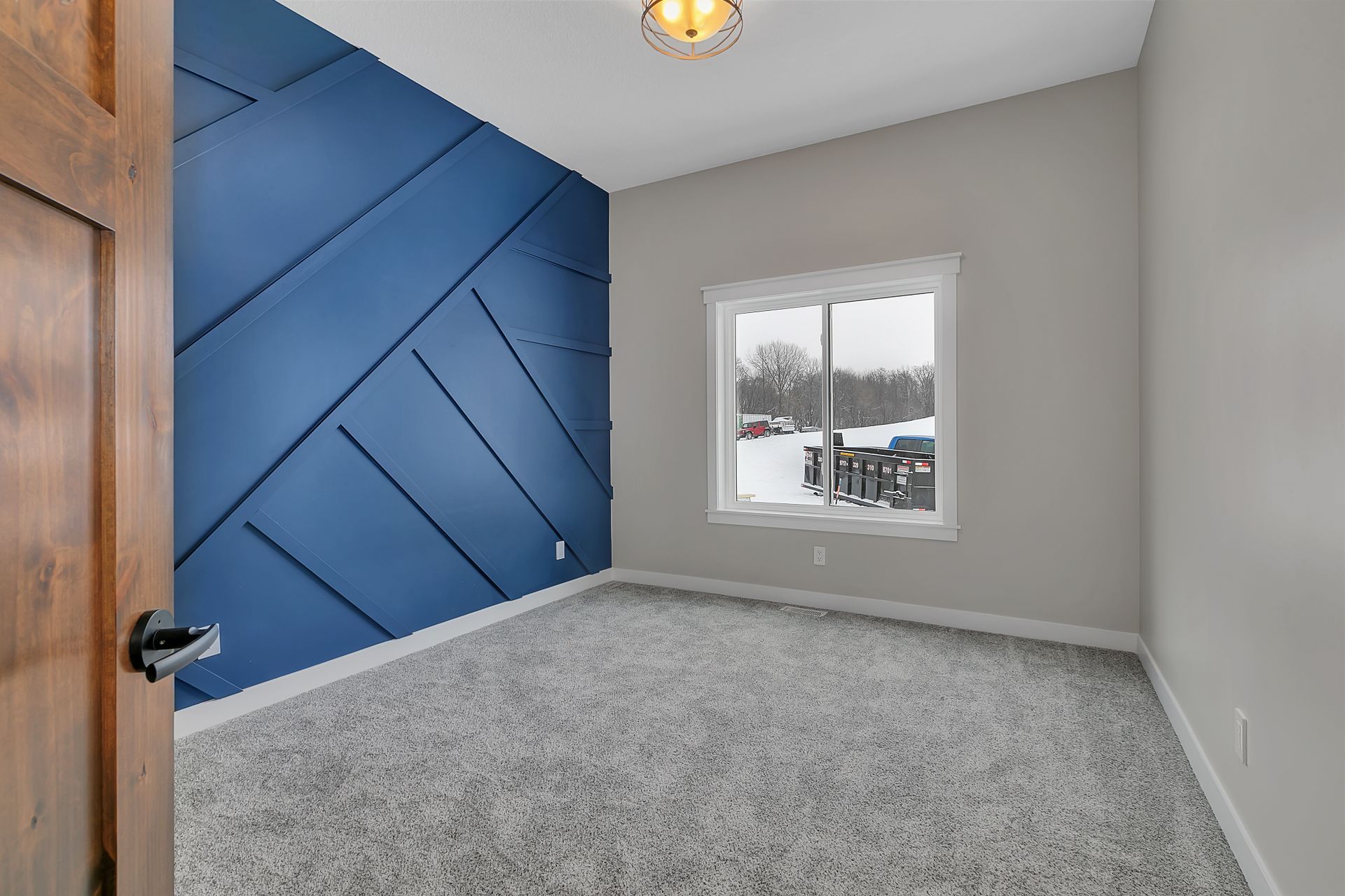 An empty bedroom with a blue wall and a window.