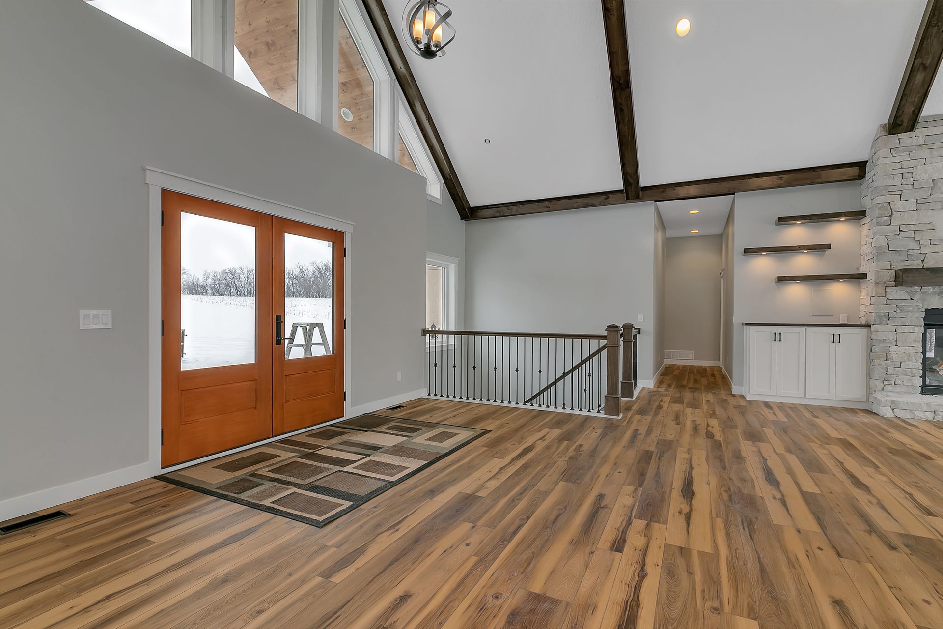 An empty living room with hardwood floors and a staircase leading to the second floor.
