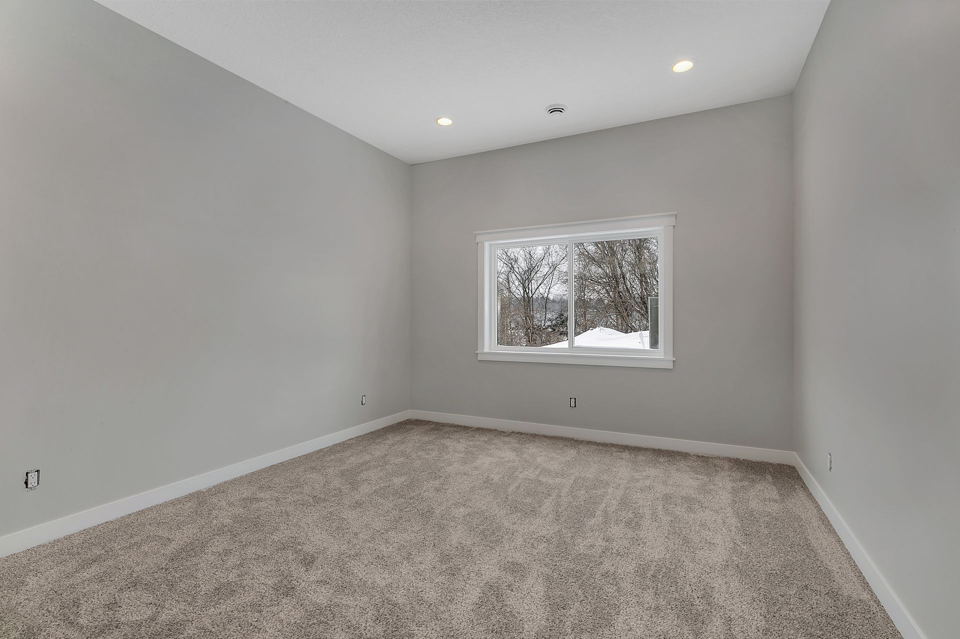 An empty room with a window and a carpeted floor.