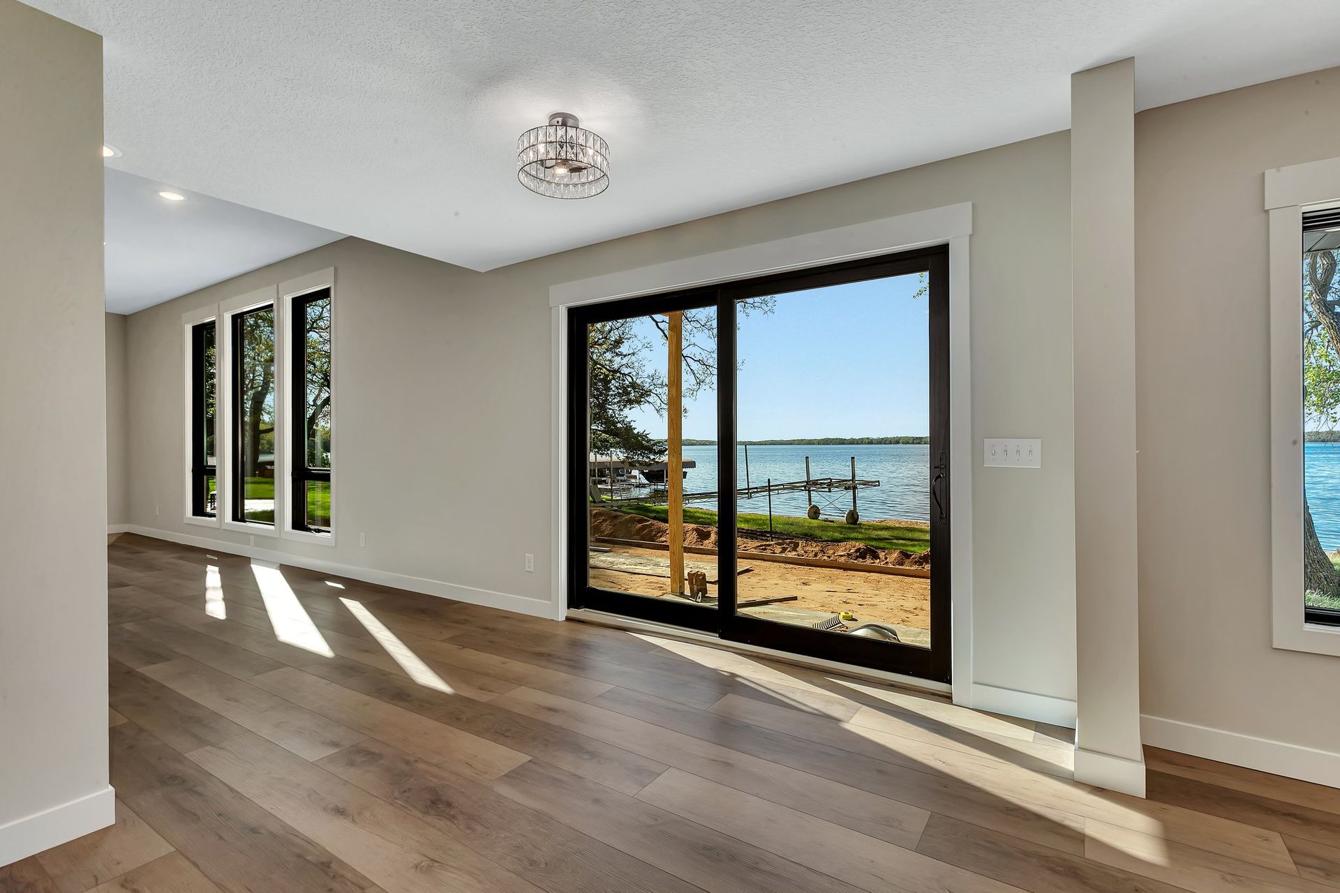 An empty room with sliding glass doors and a view of a lake.