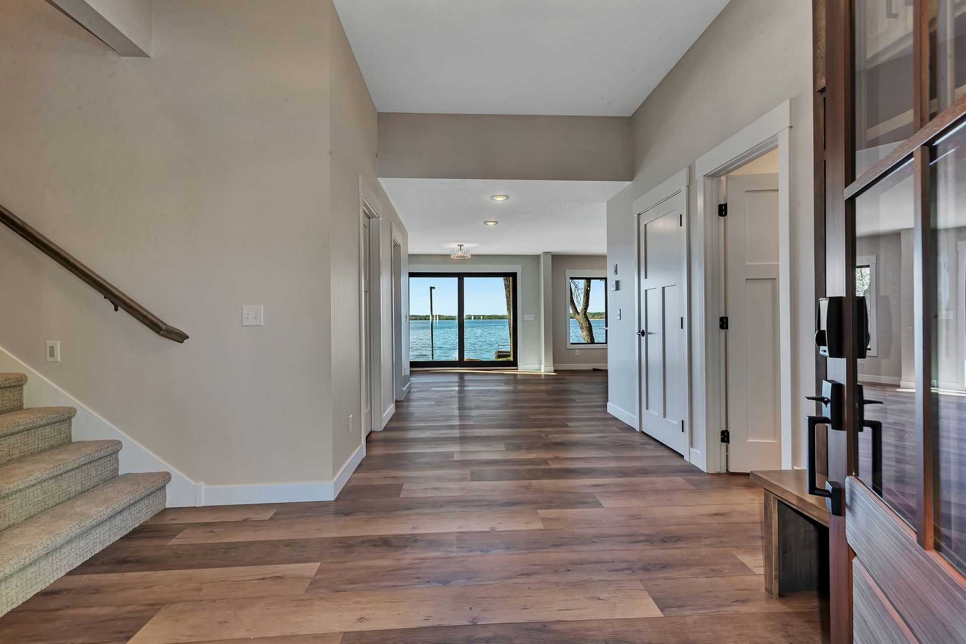 A hallway in a house with hardwood floors and stairs leading up to the second floor.
