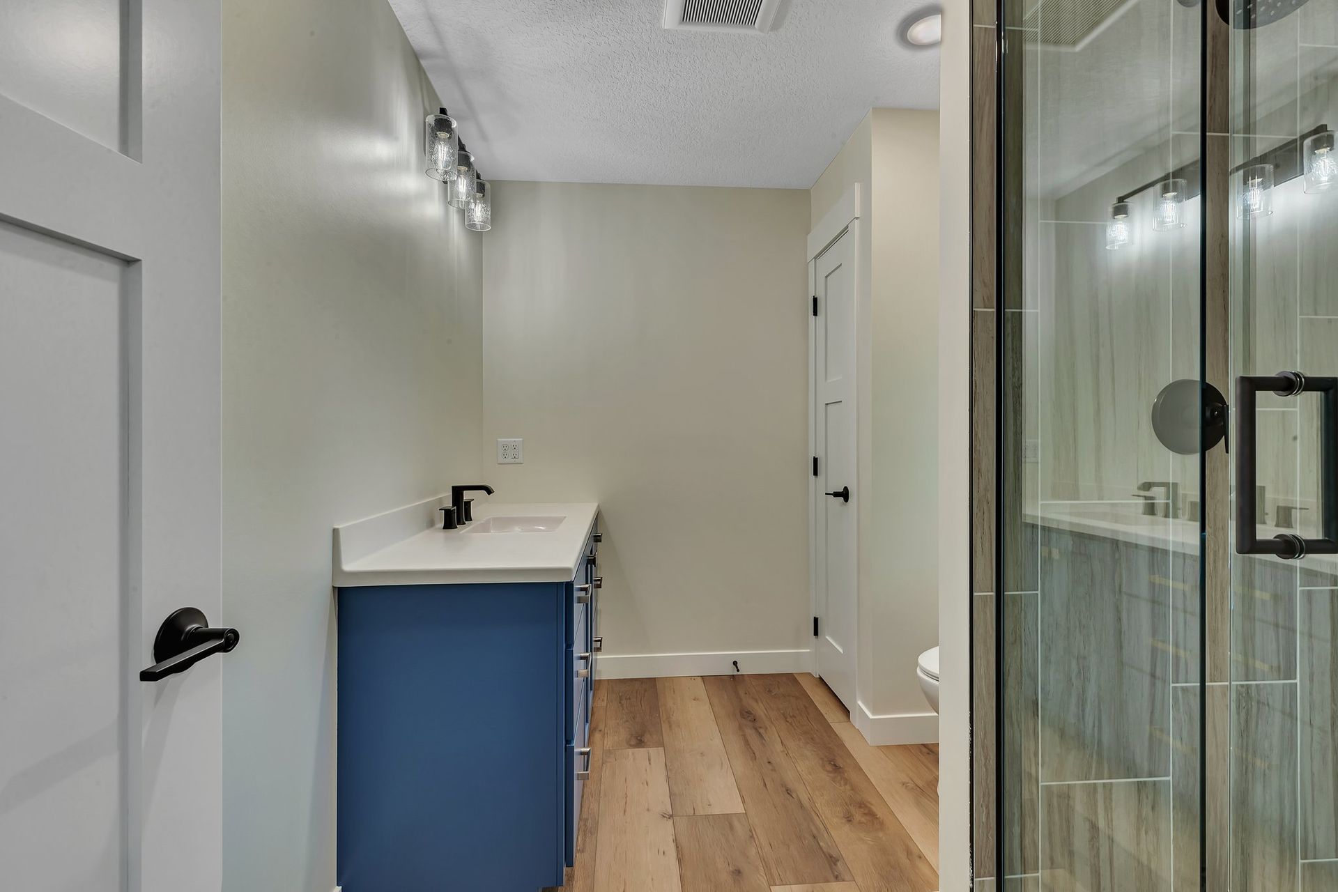 A bathroom with a blue vanity and a walk in shower.