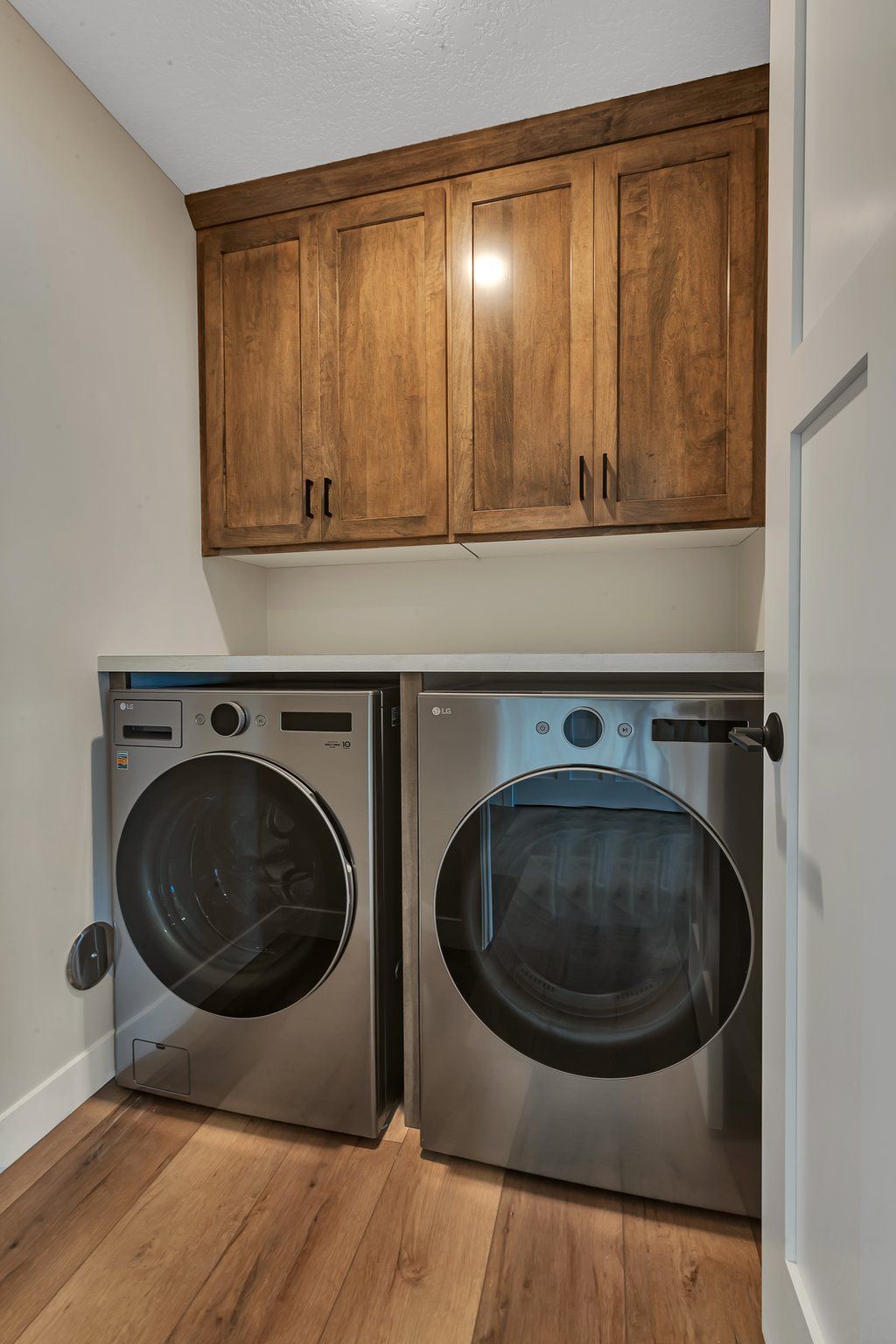 A laundry room with a washer and dryer and wooden cabinets.