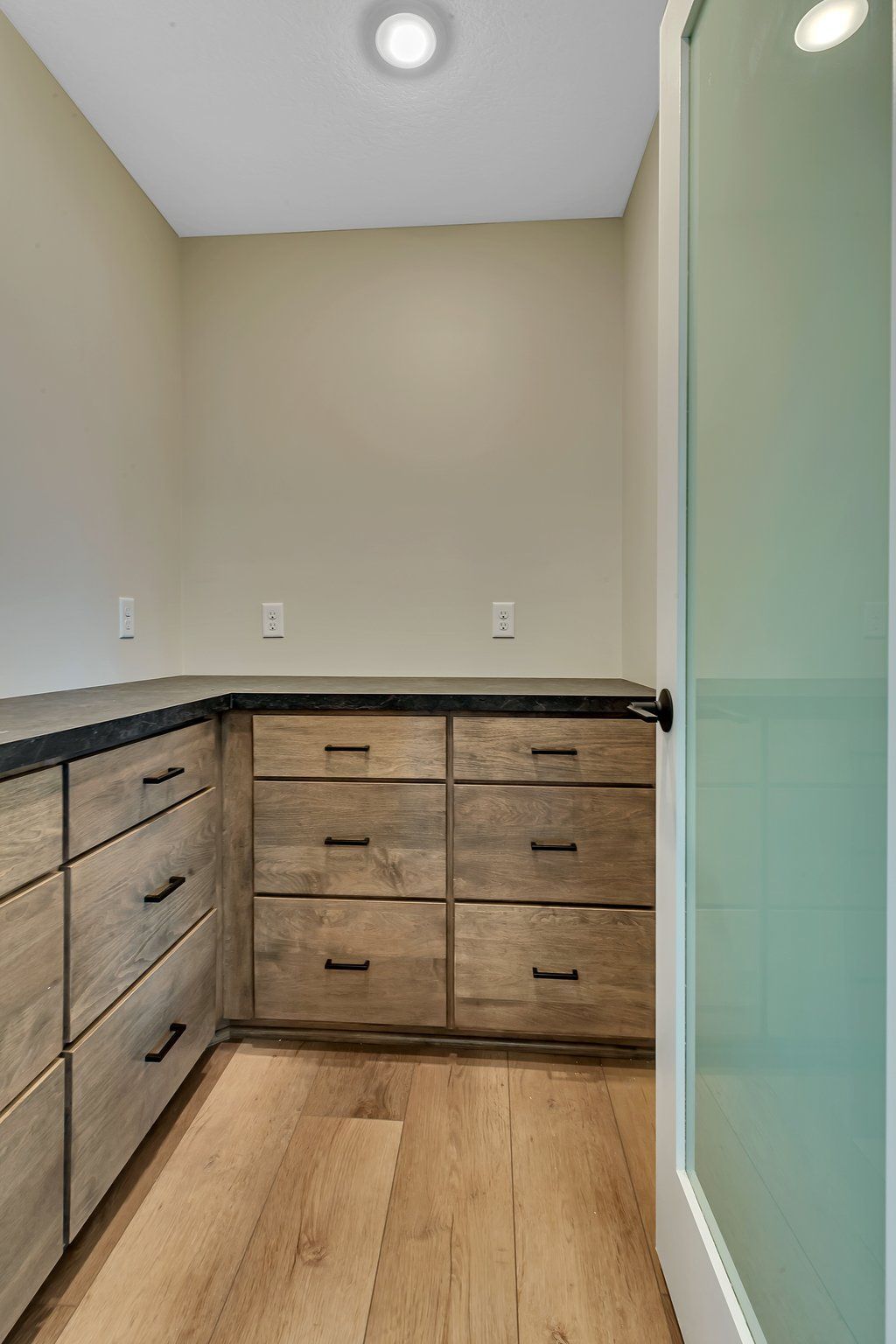 A closet with wooden drawers and a glass door.