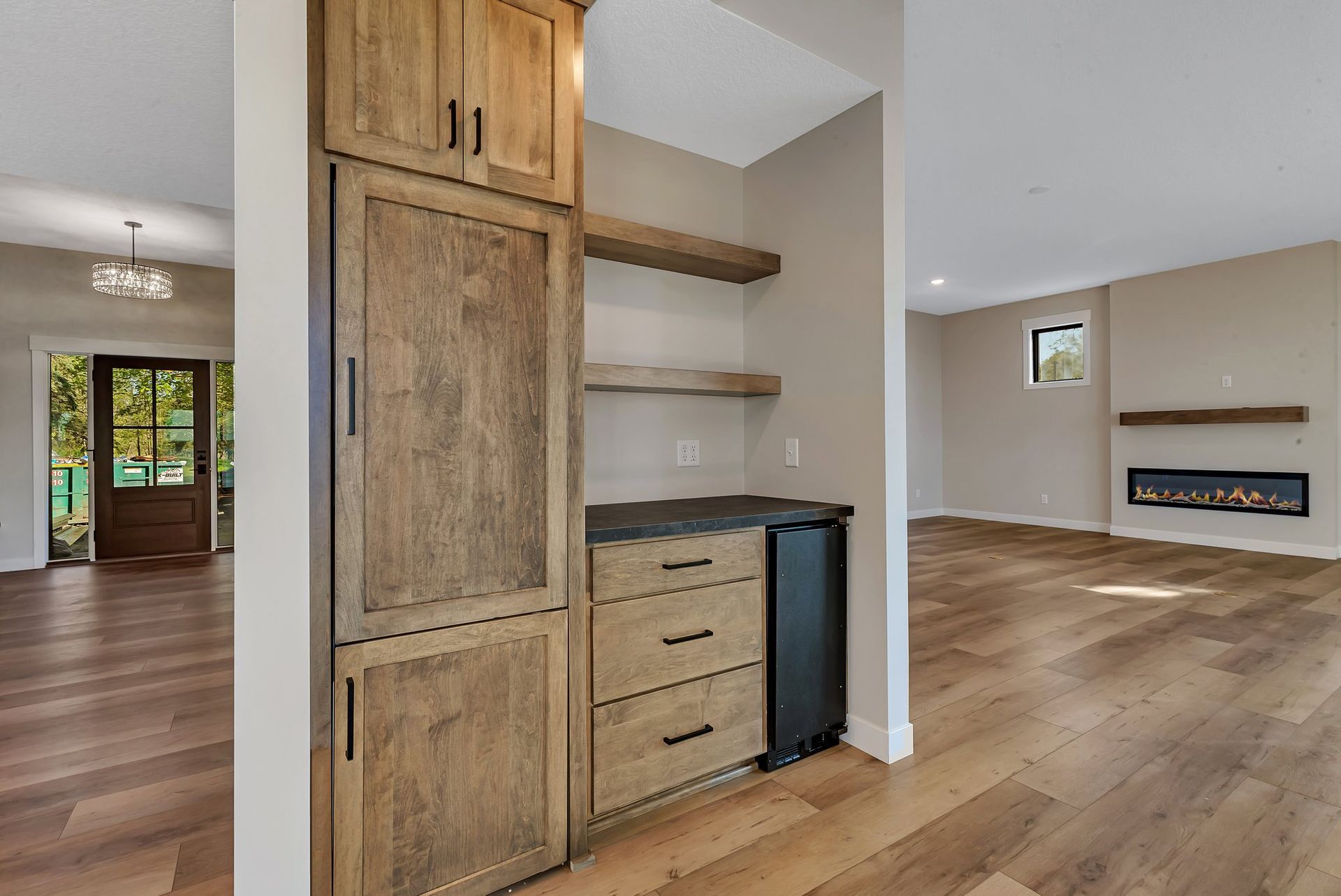A kitchen with hardwood floors , a refrigerator and a bar.