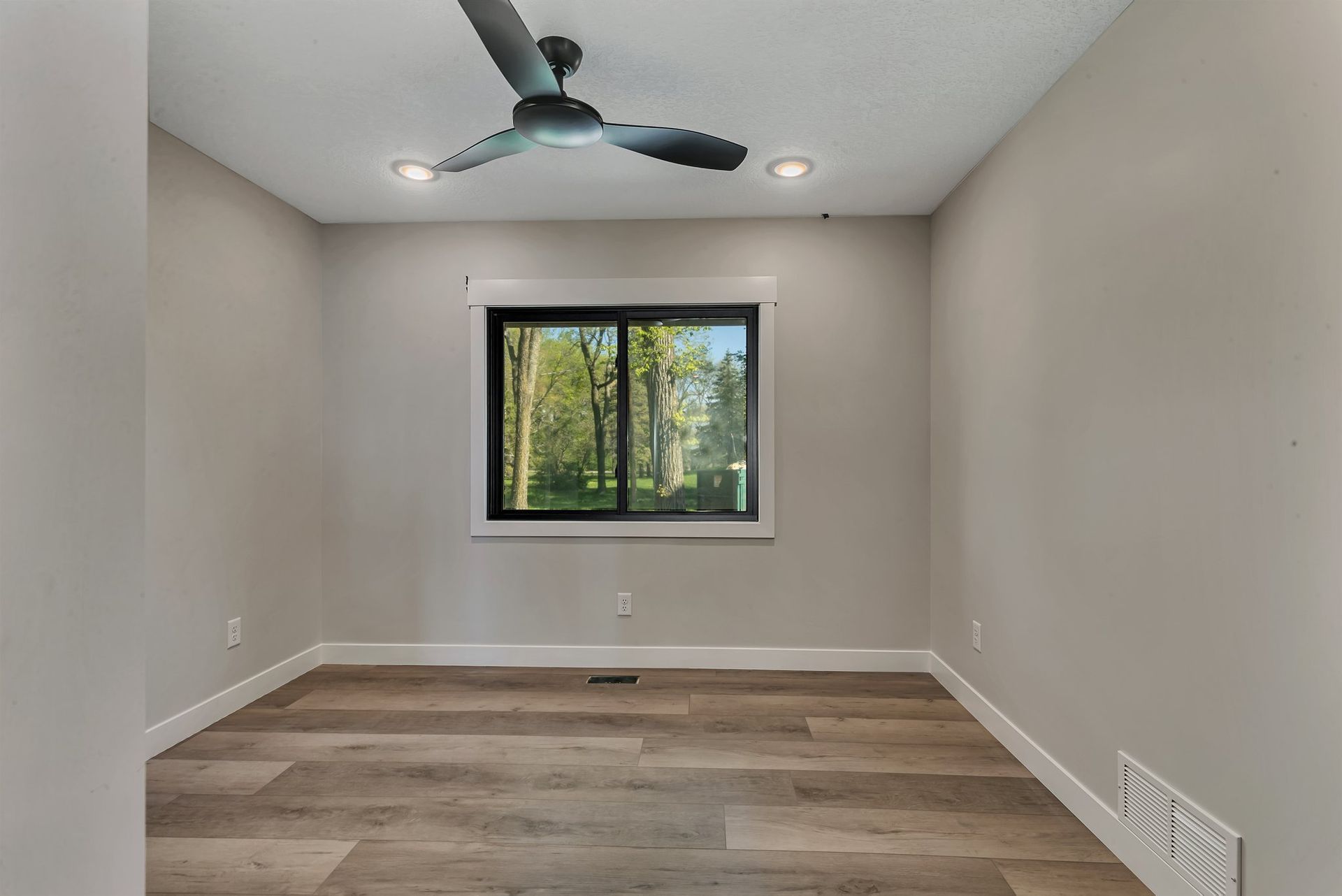 An empty room with a ceiling fan and a window.