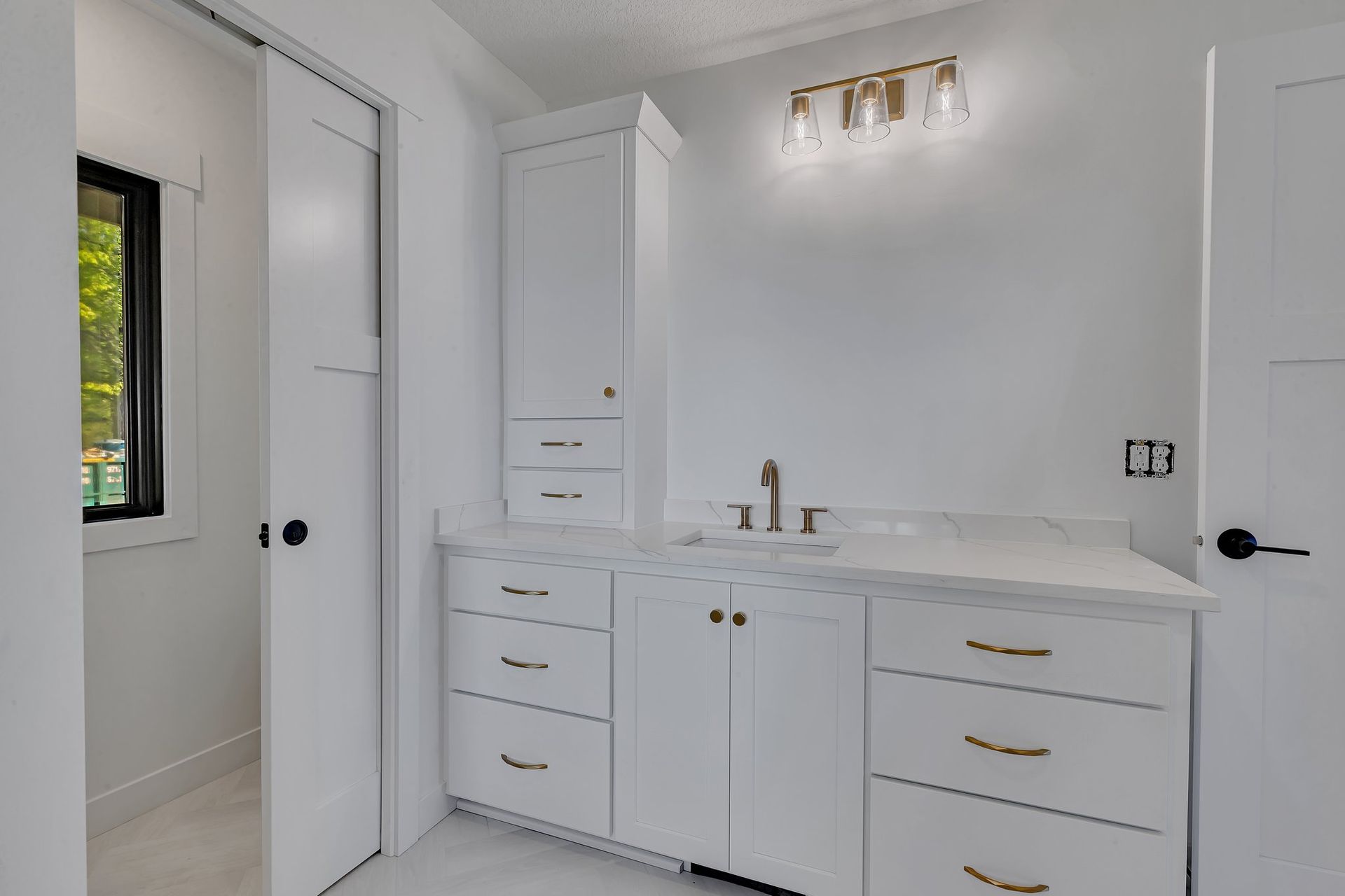 A bathroom with white cabinets and drawers and a sink.