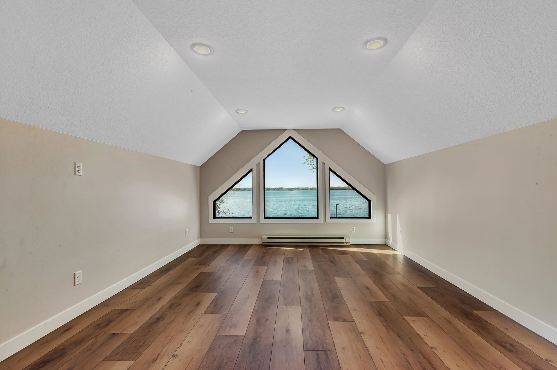 An empty room with hardwood floors and a large window.