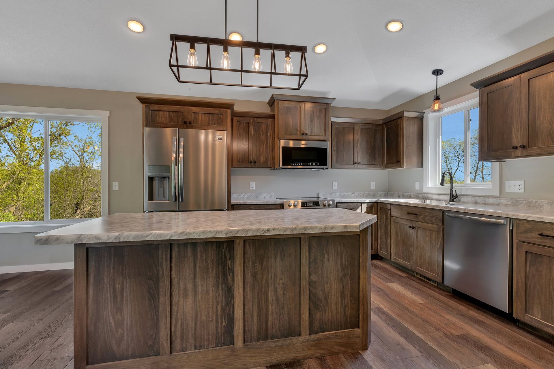 A kitchen with wooden cabinets , granite counter tops , stainless steel appliances and a large island.