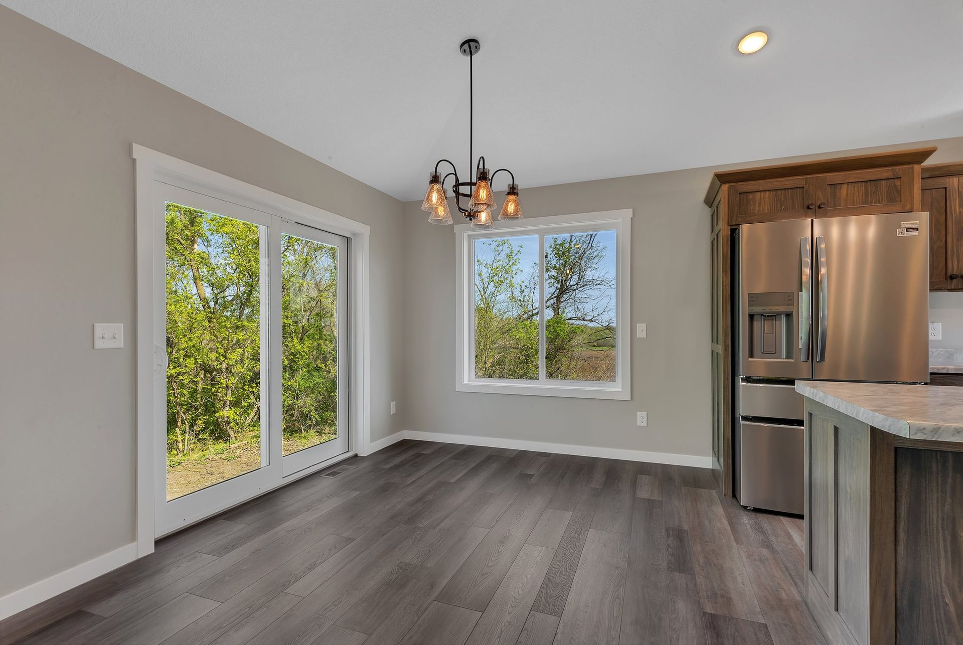 An empty kitchen with a stainless steel refrigerator and sliding glass doors.
