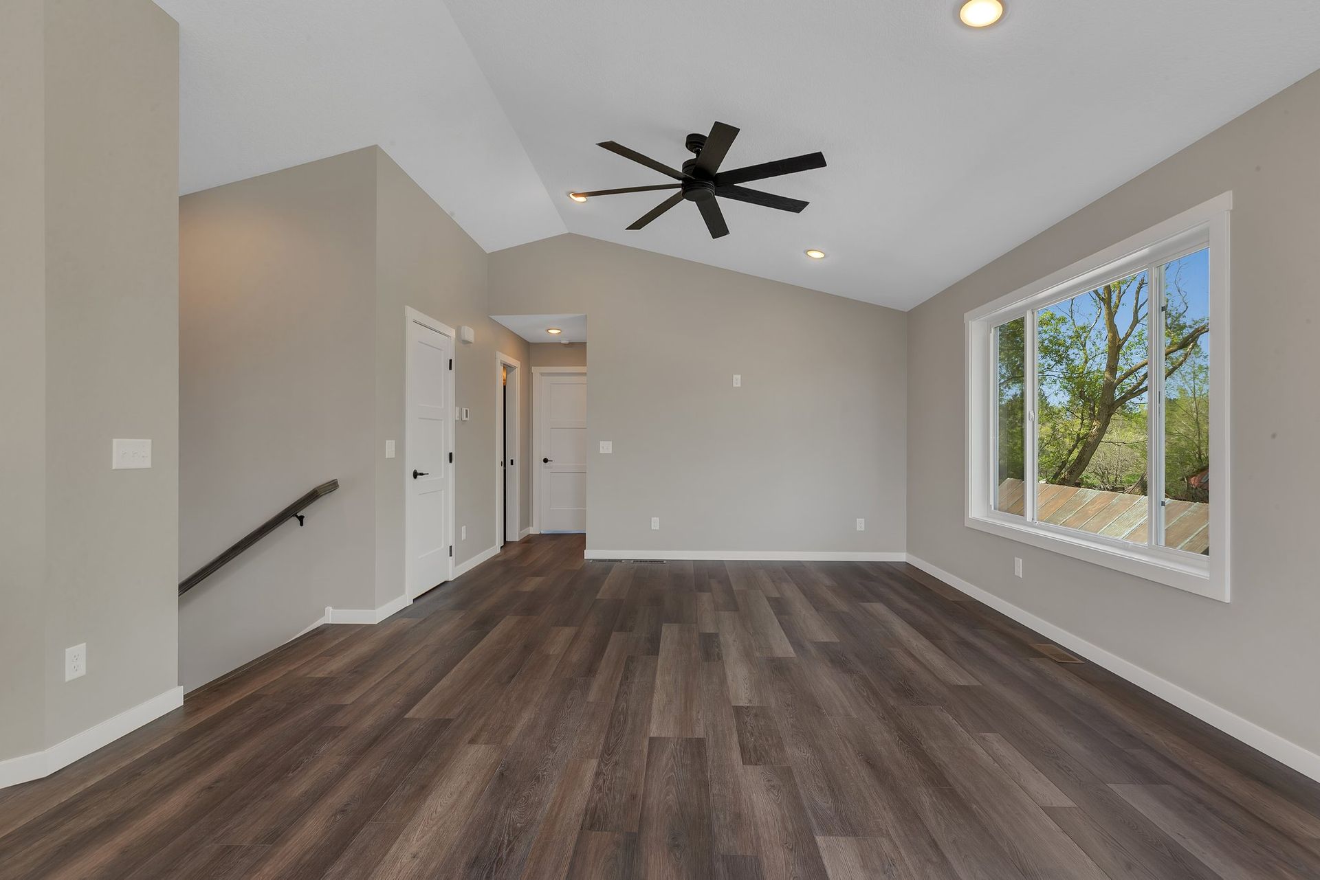 An empty living room with hardwood floors and a ceiling fan.