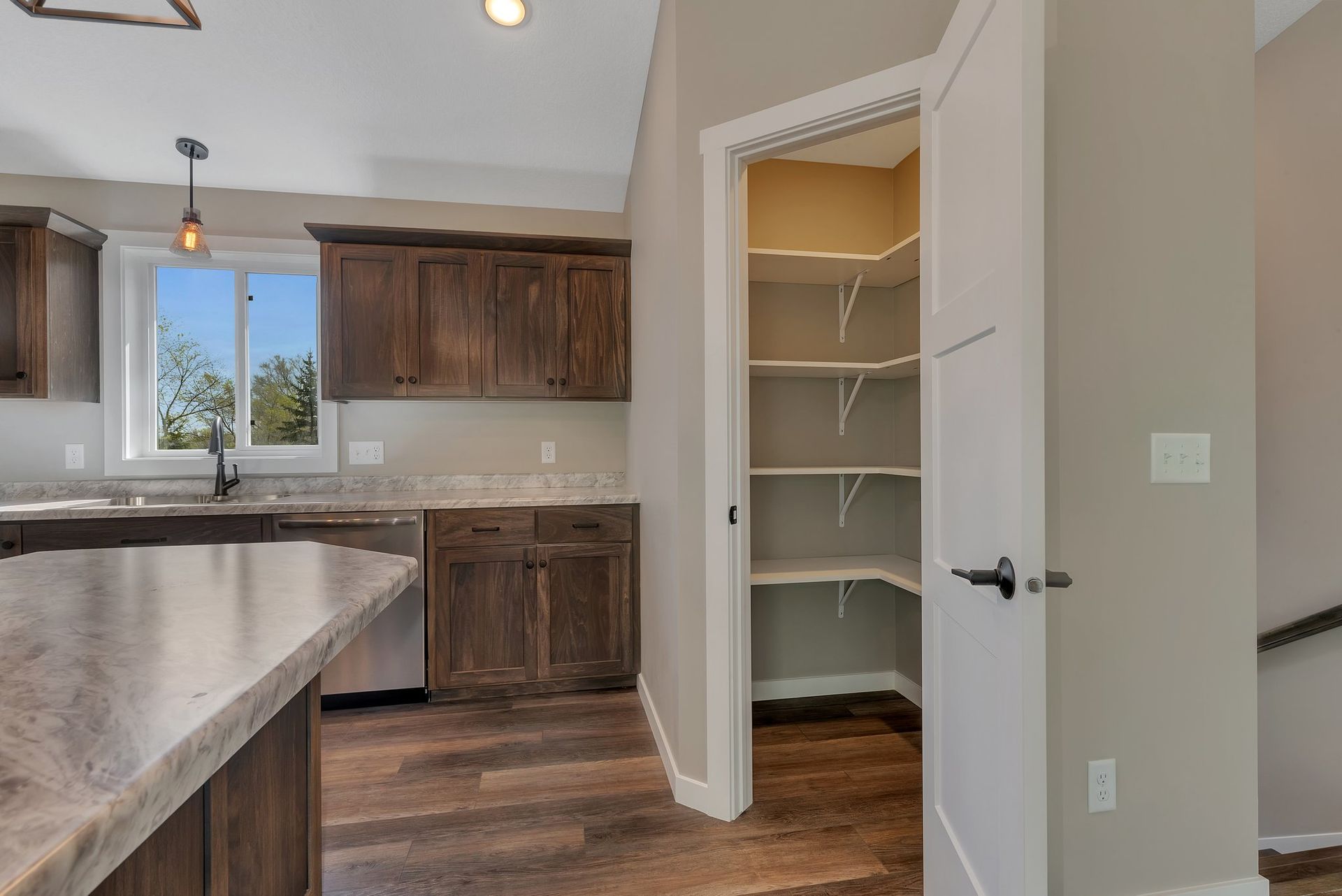 A kitchen with wooden cabinets , granite counter tops , and a pantry.