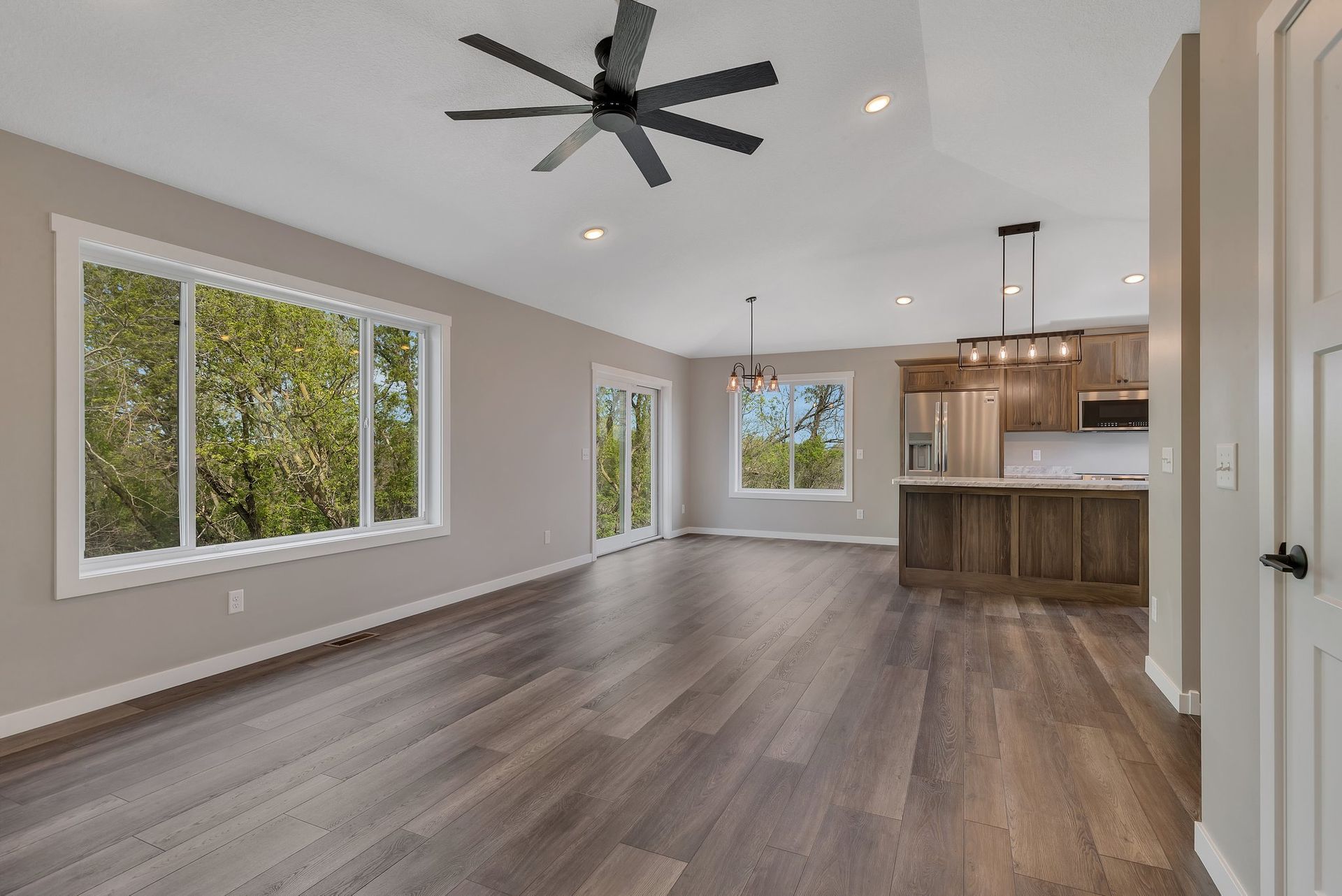 An empty living room with hardwood floors and a ceiling fan.