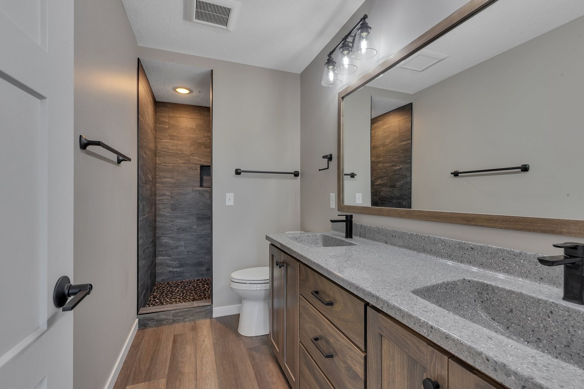 A bathroom with a toilet , sink , mirror and walk in shower.