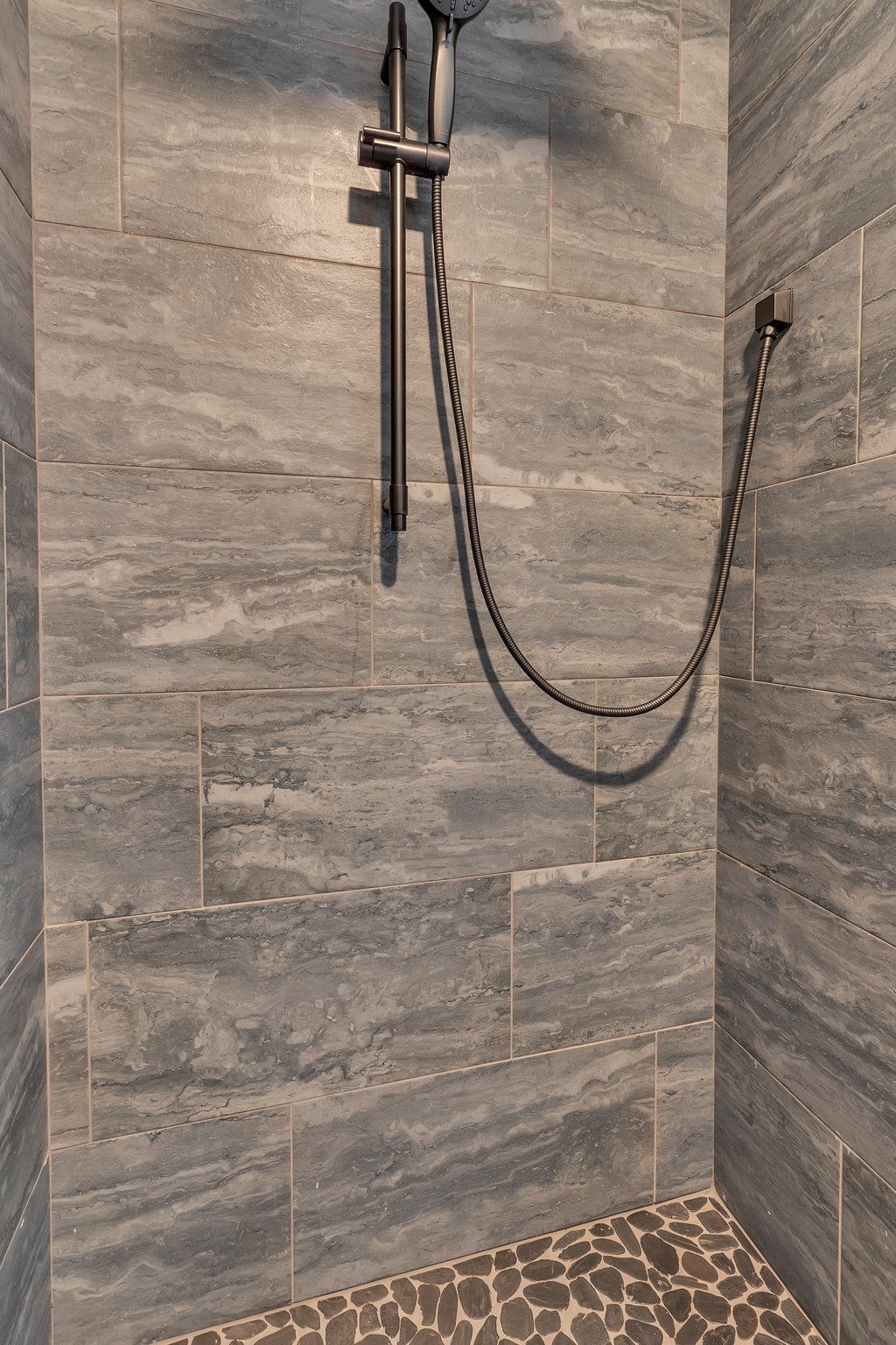 A shower with a shower head and hose attached to the wall.