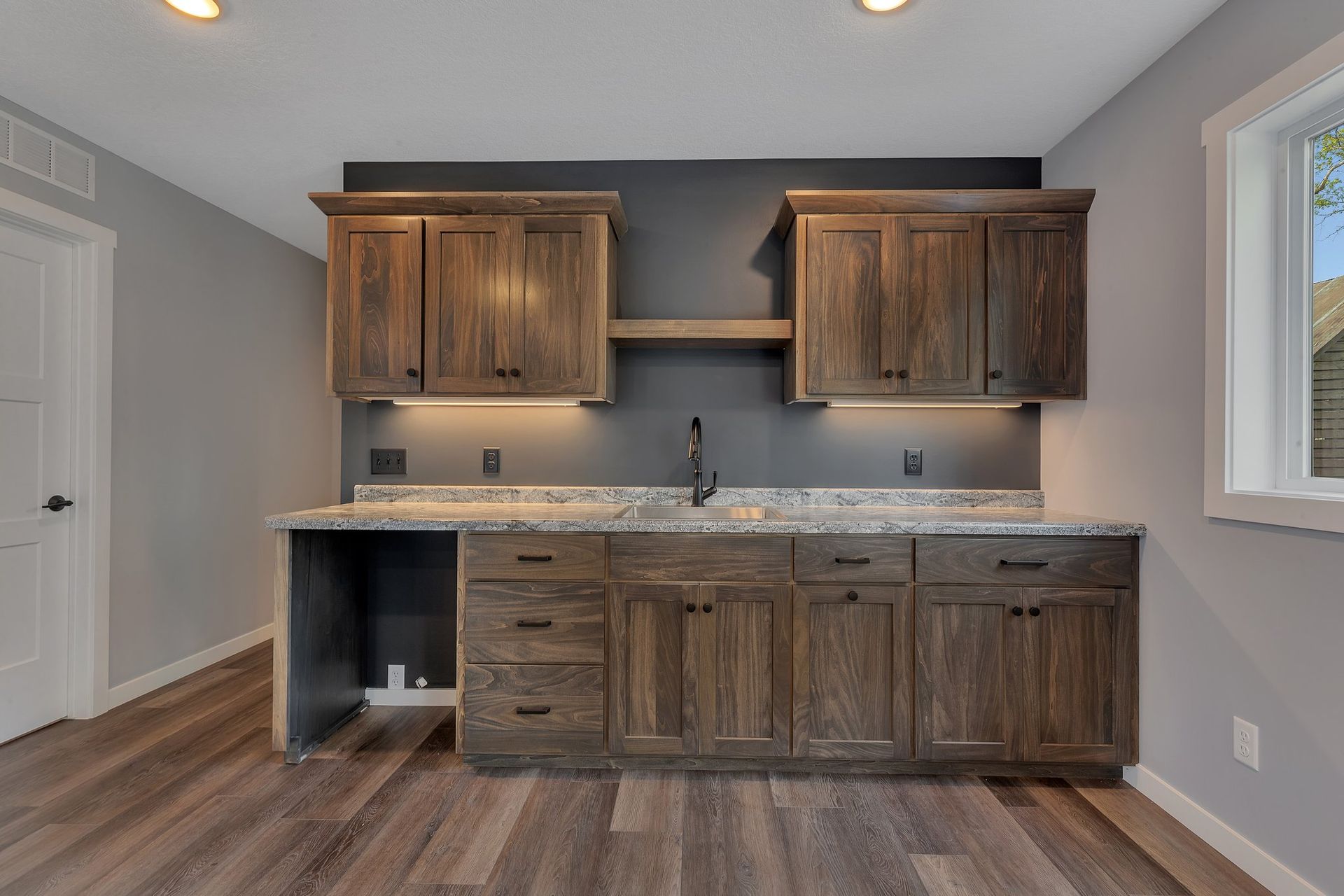 A kitchen with wooden cabinets , granite counter tops , and a sink.
