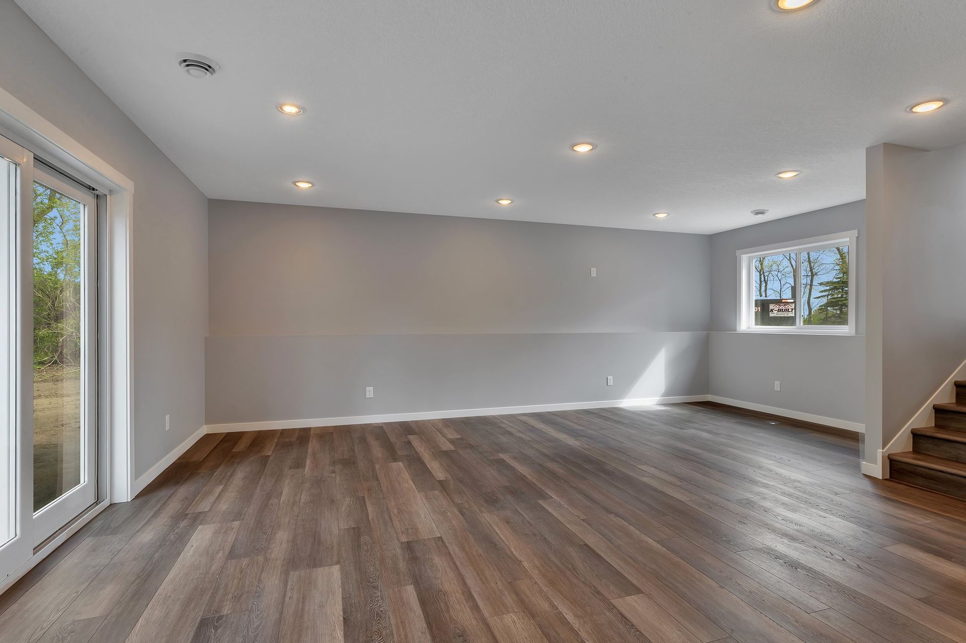 A large empty room with hardwood floors and stairs.