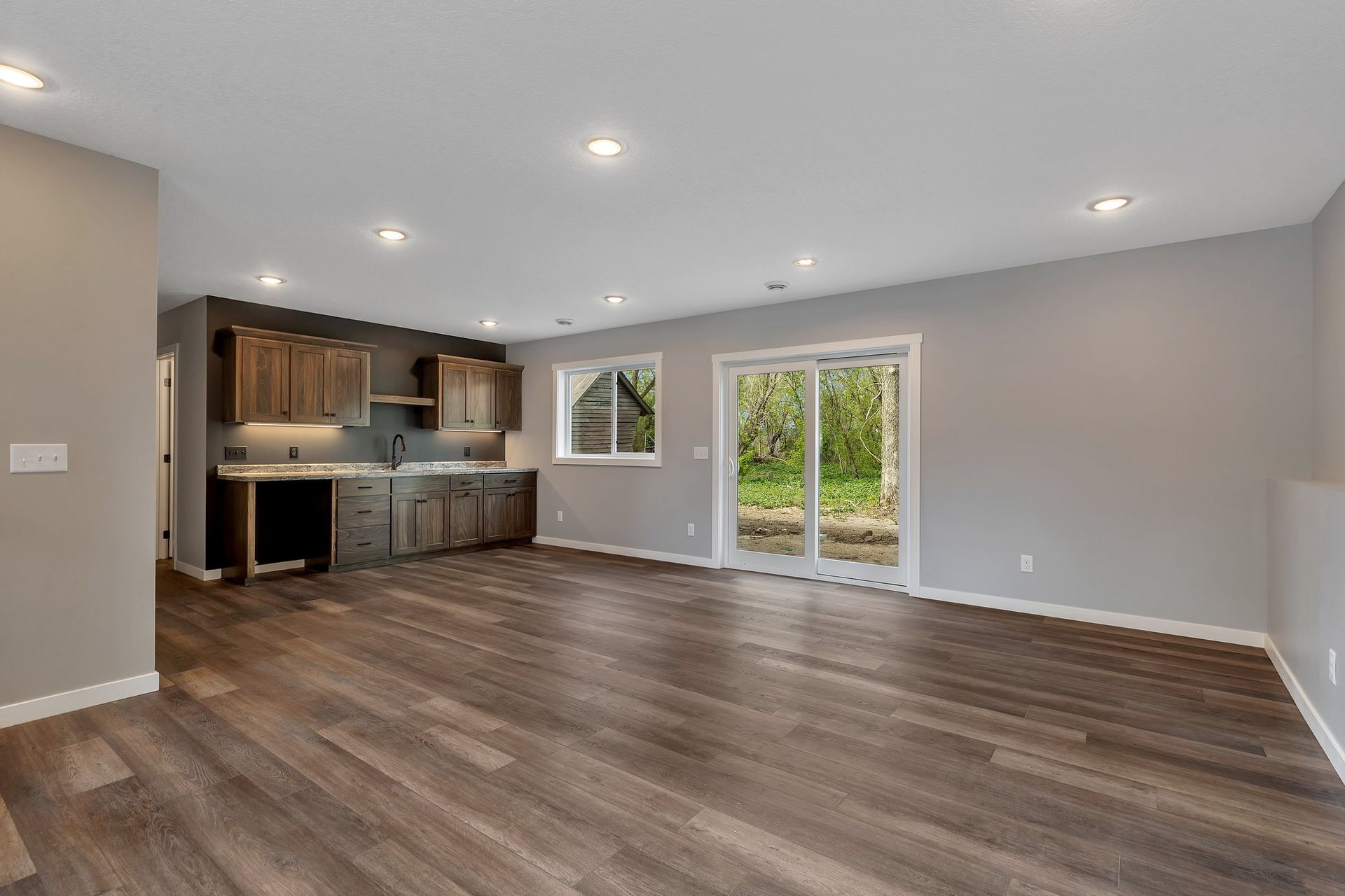 An empty living room with hardwood floors and a kitchen.