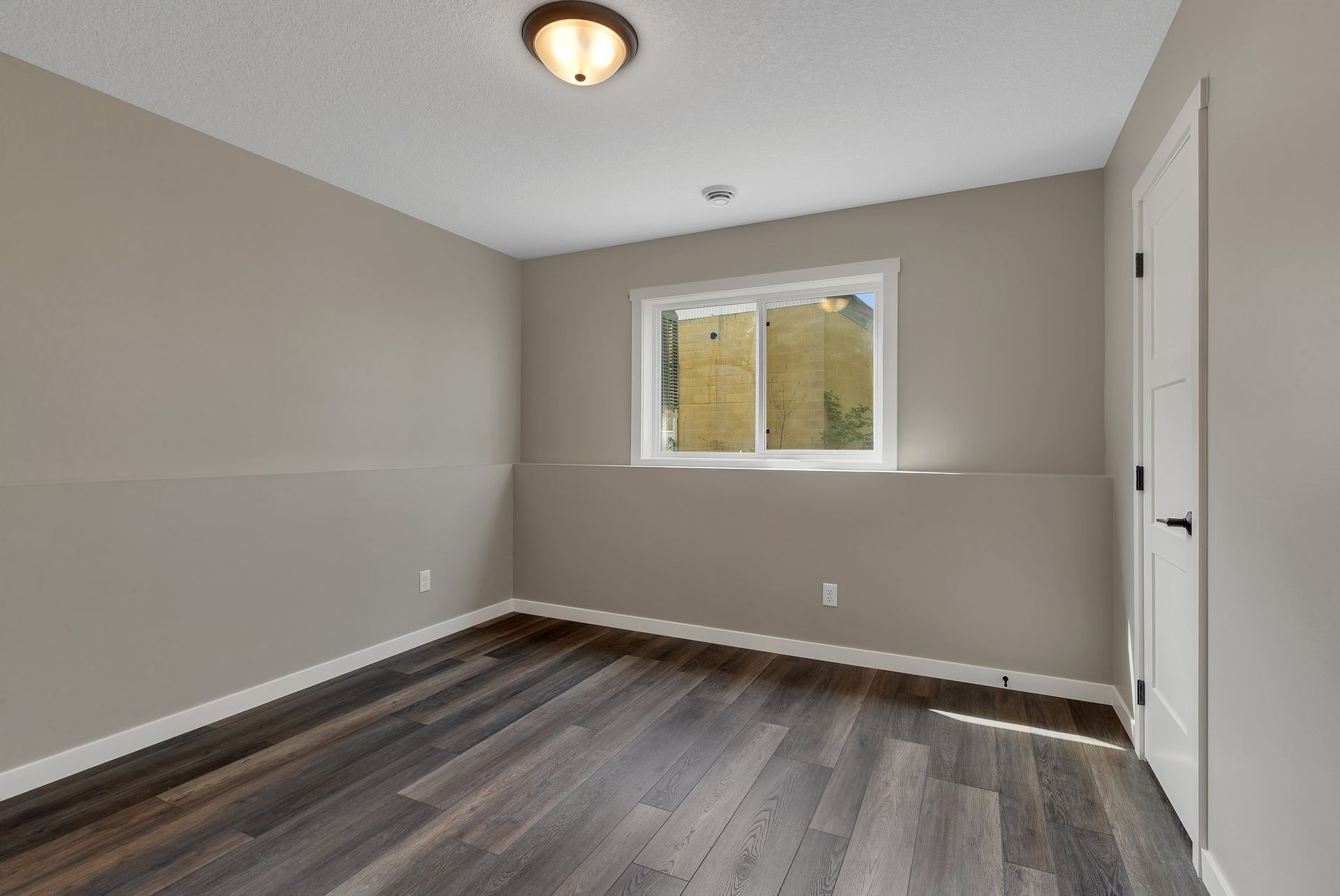 An empty room with hardwood floors and a window.