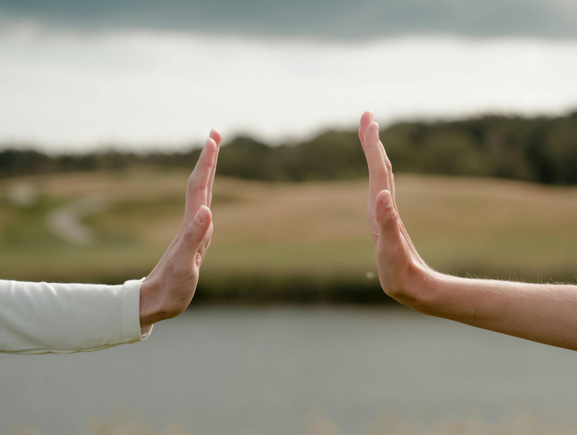 Twee handen met handpalmen naar elkaar, bijna rakend, symbool voor verbinding ontstaan in de tussenruimte tussen mensen