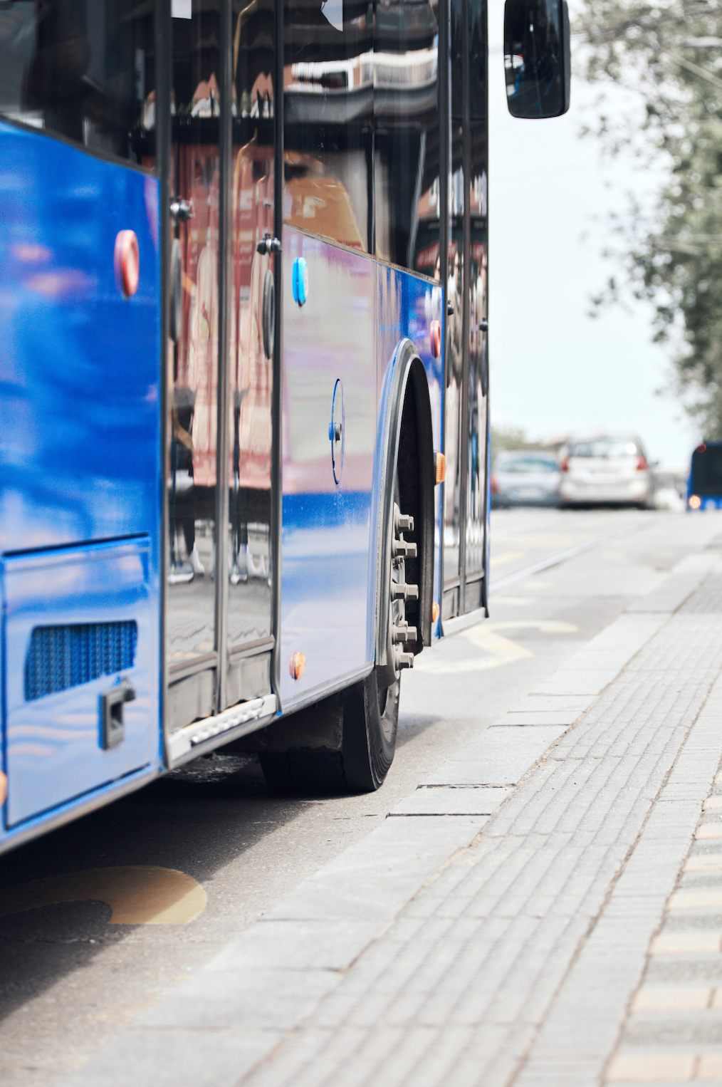 A blue bus is parked on the side of the road.