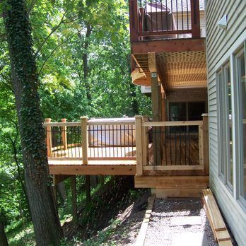 Wooden decks attached to a house, overlooking a wooded area.  A staircase leads up to one deck.