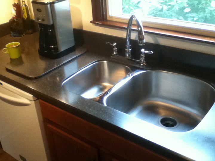 A kitchen with a stainless steel sink and a coffee maker