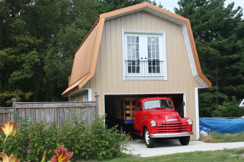 A red truck is parked in the garage of a barn