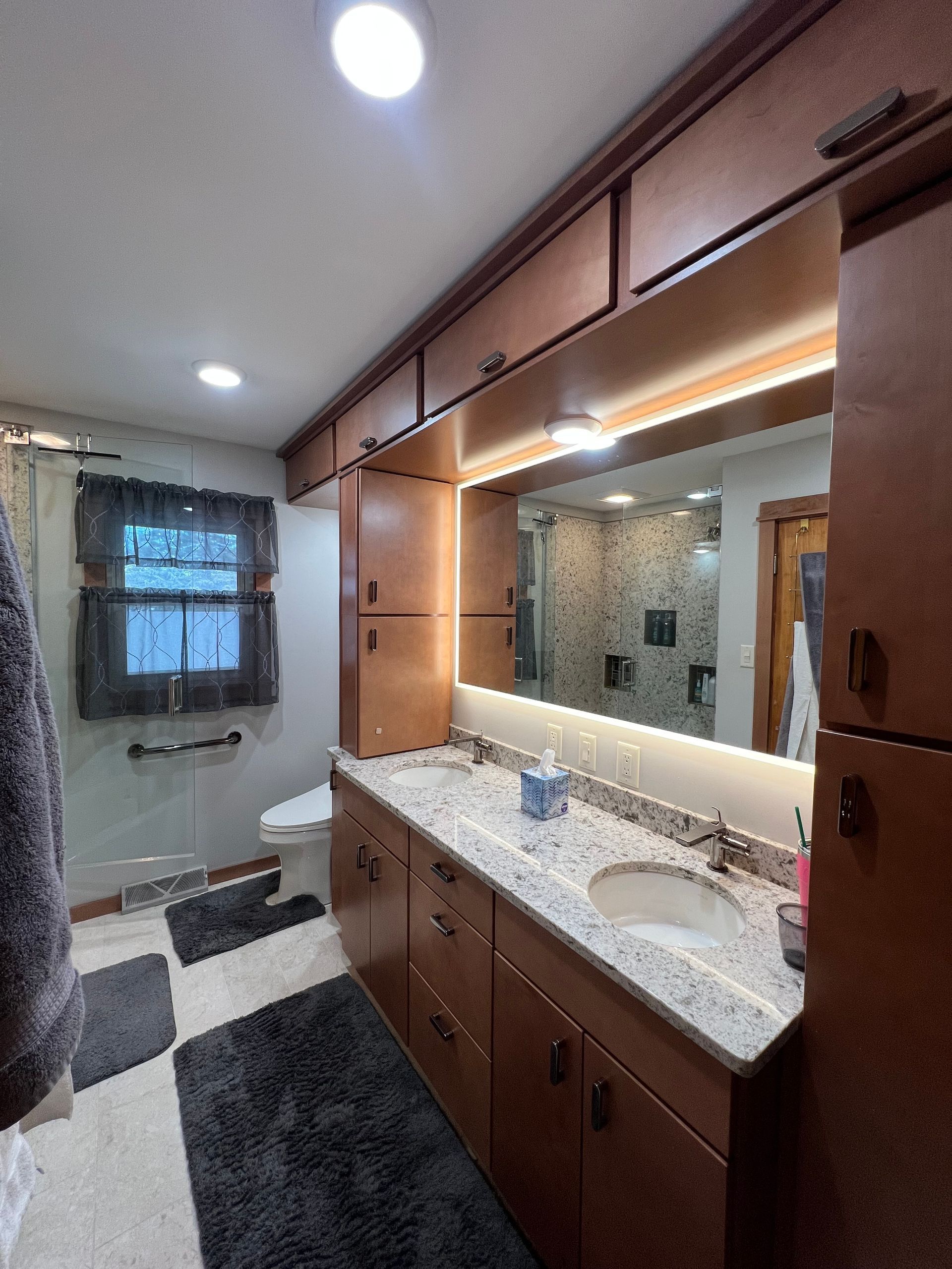 A bathroom with two sinks , a toilet , and a large mirror.