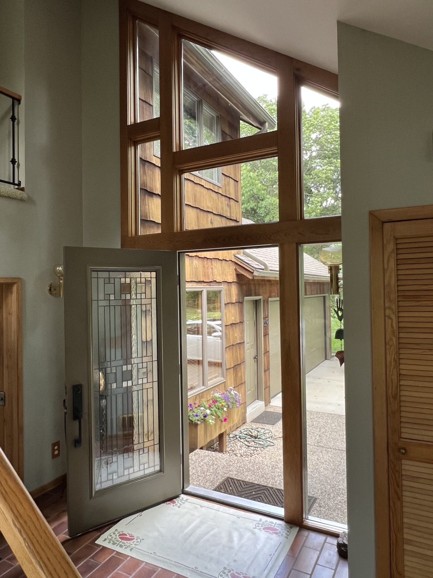 Glass entry door and tall windows opening to a covered walkway and wooden building outside