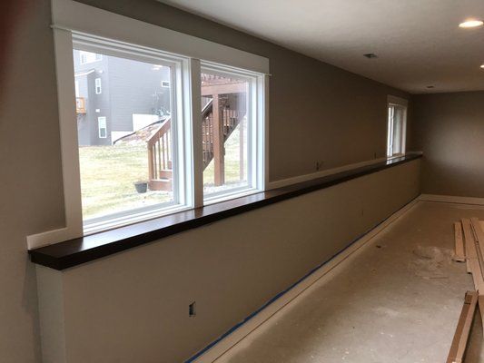 Interior view of a room with windows and a dark counter, beige walls, and light carpet.