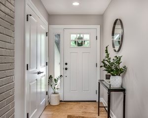 A hallway with a white door and a mirror on the wall.