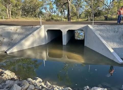 A Man is Standing Under a Bridge Over a Body of Water — Lohman Contracting in Emerald, QLD
