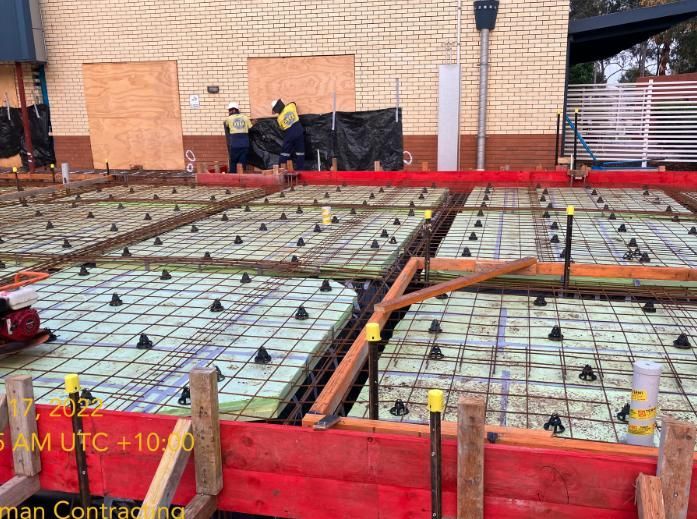 A Concrete Floor is Being Built in Front of a Brick Building — Lohman Contracting in Emerald, QLD