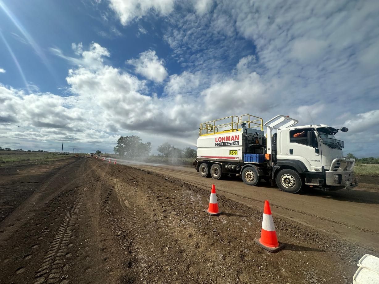 A Truck is Spraying Water on a Dirt Road — Lohman Contracting in Emerald, QLD