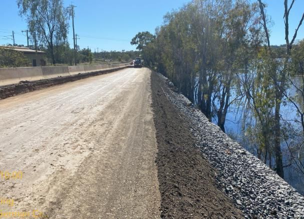 A Car is Driving Down a Dirt Road Next to a Body of Water — Lohman Contracting in Emerald, QLD