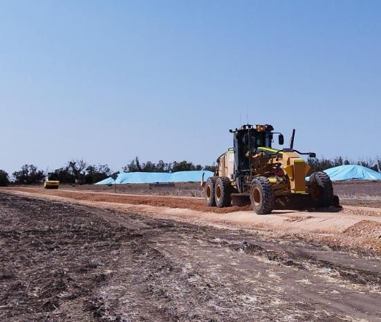 A Yellow Tractor is Driving Down a Dirt Road — Lohman Contracting in Emerald, QLD