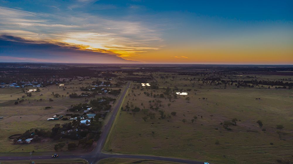An Aerial View Of A Sunset Over A Rural Area With A Road Going Through It — Lohman Contracting in Roma, QLD