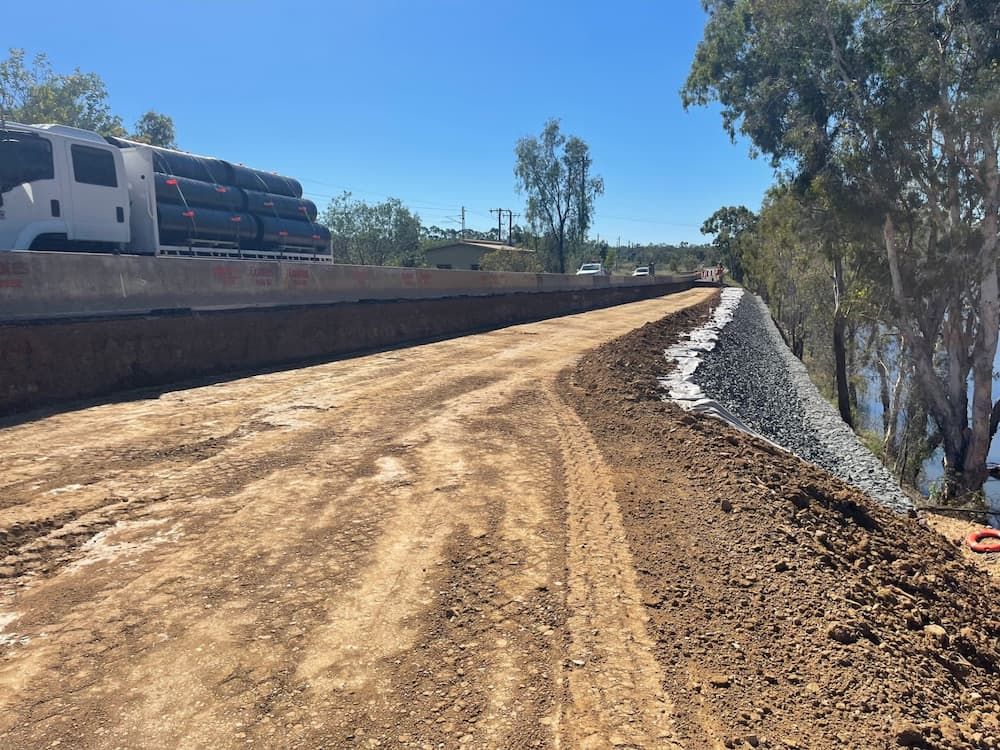 A Truck Is Driving Down A Dirt Road Next To A Body Of Water — Lohman Contracting in Emerald, QLD