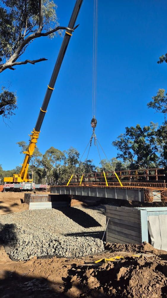 A Crane Is Lifting A Bridge Over A River — Lohman Contracting in Biloela, QLD