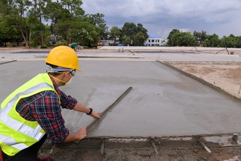 A Construction Worker Is Measuring A Concrete Surface With A Ruler — Lohman Contracting in Roma, QLD