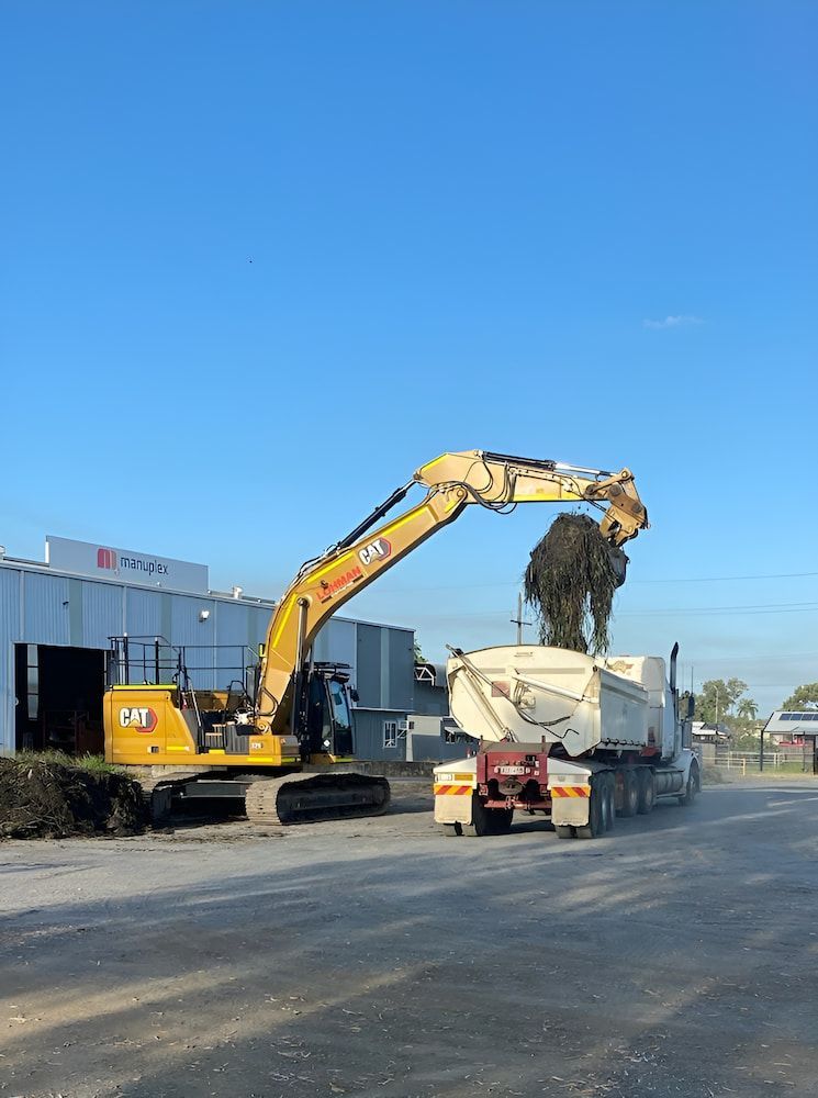 A Yellow Excavator Is Loading A Dump Truck With Dirt — Lohman Contracting in Emerald, QLD