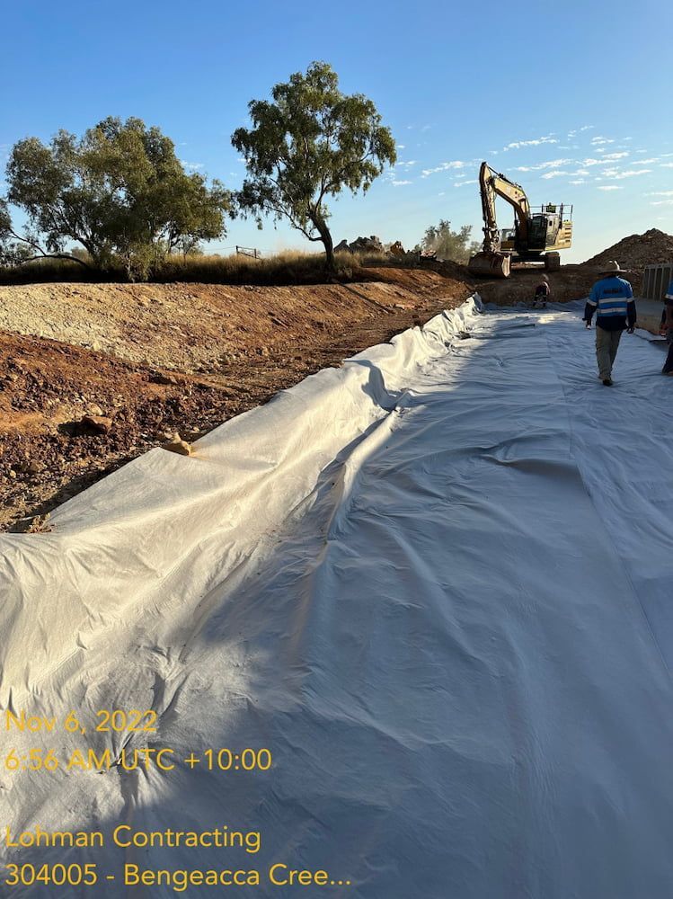 A Man Is Walking Down A Dirt Road Next To A Large White Tarp — Lohman Contracting in Katherine, NT