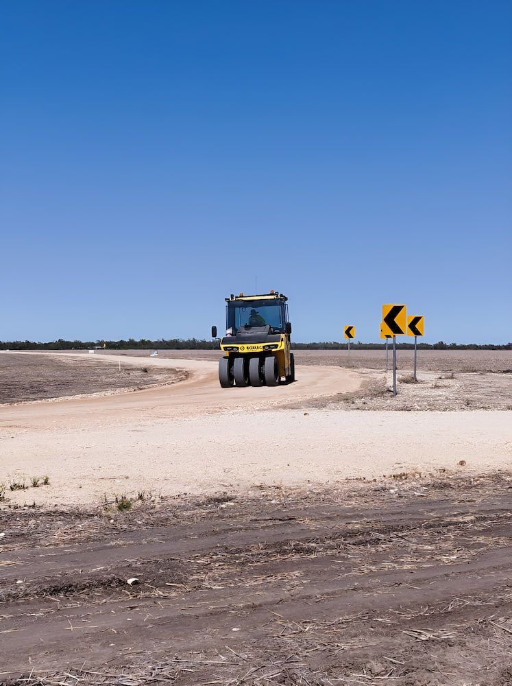 A Yellow Truck Is Driving Down A Dirt Road — Lohman Contracting in Emerald, QLD
