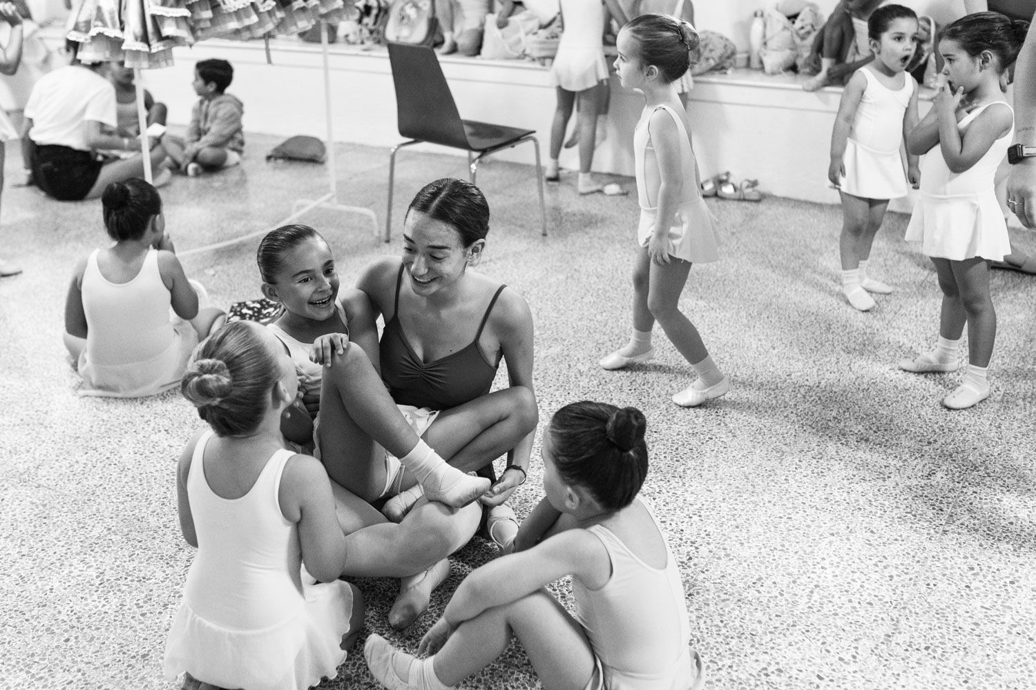 Un grupo de chicas jóvenes están sentadas en el suelo en un estudio de danza.